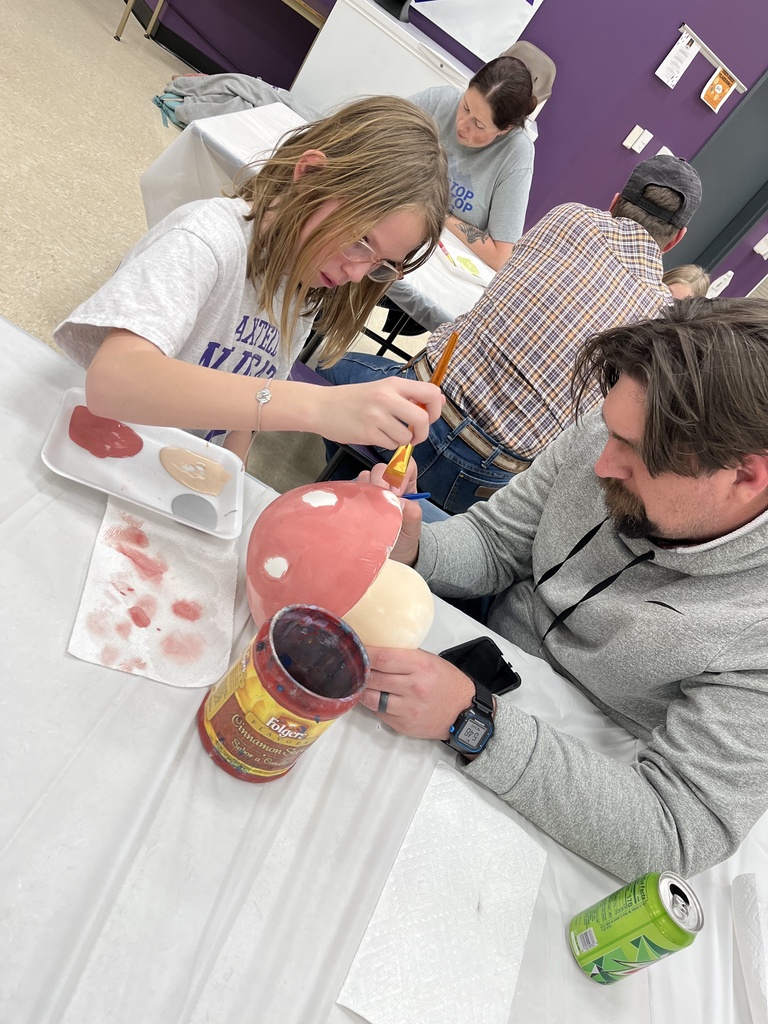 A daughter and father painting a piece of pottery together 