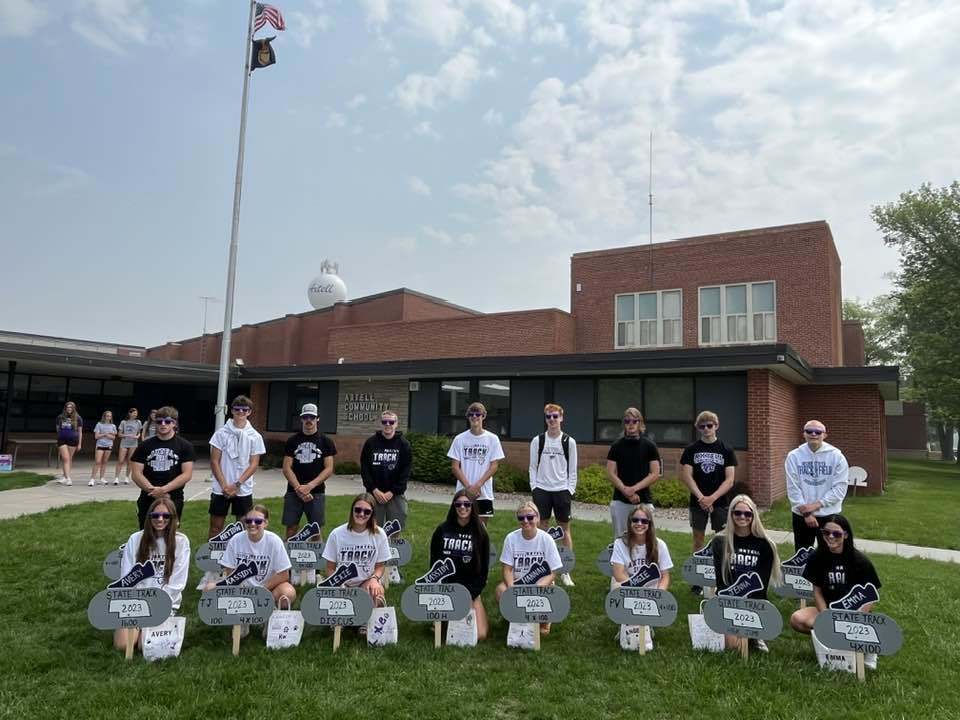 state track athletes posing in front of signs