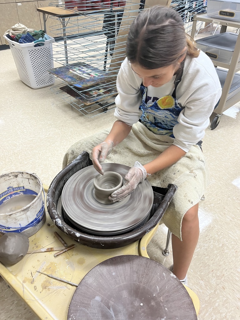student throwing on the pottery wheel. 